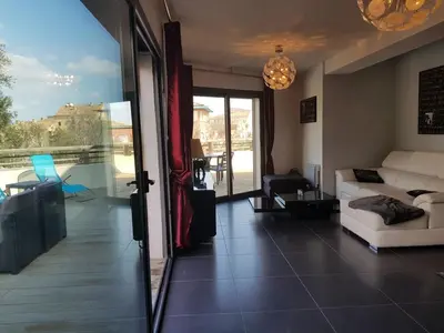a living room with a white couch and a balcony at APPARTEMENT TERRASSE CITA DI SALI PORTO VECCHIO in Porto-Vecchio
