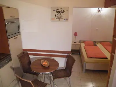a small kitchen with a table and a room at Villa Liamone Studio für 3 Personen , 400 m vom Strand, Pool, Klimaanlage in Sagone
