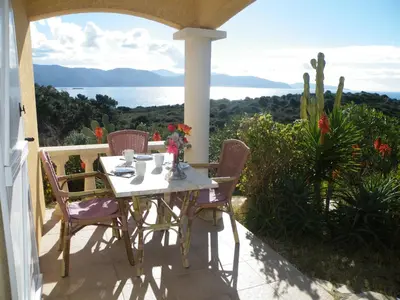 a table and chairs on a porch with a view of the ocean at Villa Liamone Studio für 3 Personen , 400 m vom Strand, Pool, Klimaanlage in Sagone
