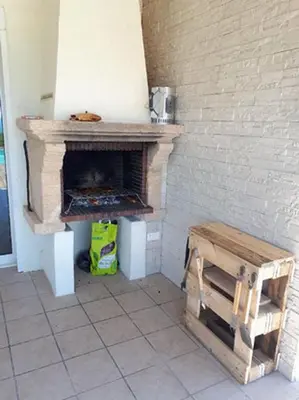 a room with a stone fireplace with a wooden stool at Sole Rossu in Albitreccia