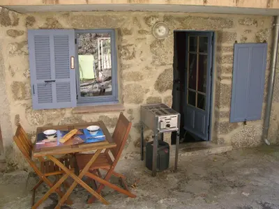 a table and chairs next to a building with a window at mare-monte in Evisa
