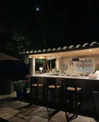 an outdoor bar with stools in a kitchen at night at Residence VILLA MOROSI - Favone in Conca