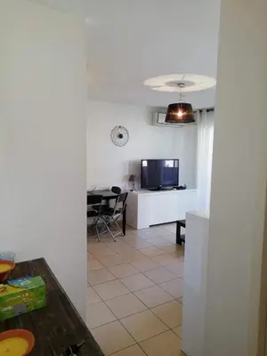 a kitchen and living room with a table and a tv at Les princes du golf Jerome numero 13 quartier pascal paoli Appartement in Porto-Vecchio