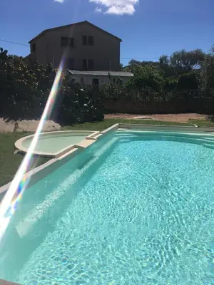 a large swimming pool with a rainbow in front of a house at Les princes du golf Jerome numero 13 quartier pascal paoli Appartement in Porto-Vecchio