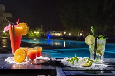 a table with drinks on it next to a pool at Suite Home Porticcio in Porticcio