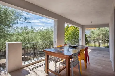 a dining room with a table and chairs on a balcony at Villa Le Corps de Garde in Furiani