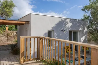 a small white house with a wooden railing at Villa Le Corps de Garde in Furiani