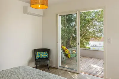 a bedroom with a sliding glass door and a chair at Villa Le Corps de Garde in Furiani