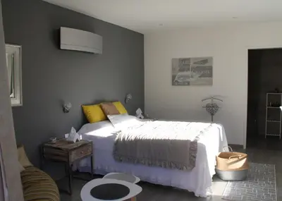 a bedroom with a white bed and a table at L'oliveraie du Fango in Manso