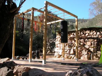 a wooden structure in front of a stone wall at L'oliveraie du Fango in Manso