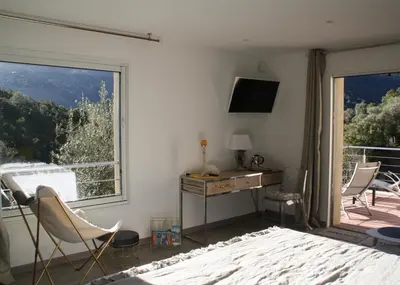 a bedroom with a large window and a desk and chairs at L'oliveraie du Fango in Manso