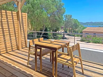 a wooden table and two chairs on a deck at Hôtel Maora Village in Bonifacio