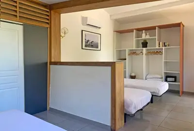 a bedroom with two beds and a large mirror at Hôtel Maora Village in Bonifacio