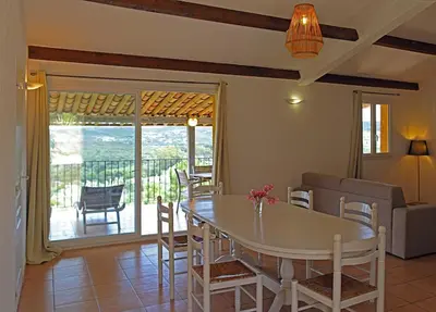 a living room with a table and chairs and a balcony at Résidence Maora Village in Bonifacio