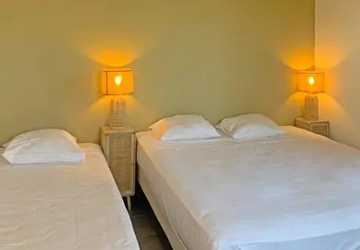 two beds in a room with two lamps on the wall at Résidence Maora Village in Bonifacio
