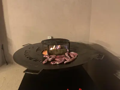 a stone fireplace with meat and a candle on it at Hotel U Liccedu in Bustanico