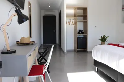 a bedroom with a bed and a desk with a lamp at Hotel Fazio in Bonifacio