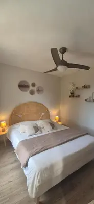 a bedroom with a large bed with a ceiling fan at Gîte A l'ombre du clocher in Calenzana