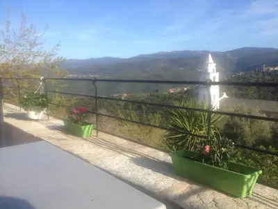a balcony with two potted plants and a white church at Casa di Emma in Santo-Pietro-di-Tenda