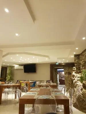a dining room with tables and chairs and a television at A COSTA in Venzolasca