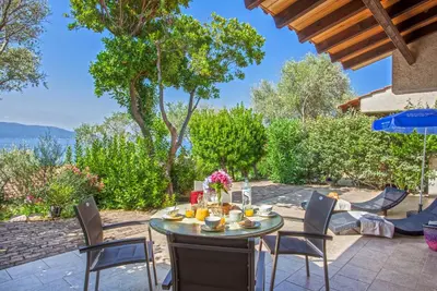 a table and chairs on a patio with a view of the ocean at Résidence Arco Plage in Olmeto