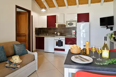 a kitchen with a couch and a table with wine glasses at Résidence Arco Plage in Olmeto
