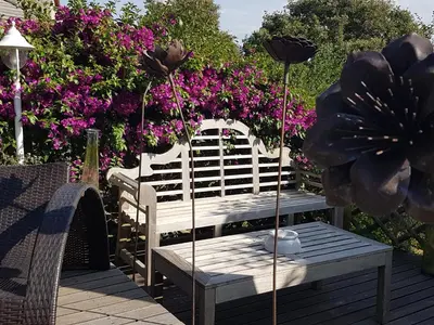 a wooden bench sitting on a deck with flowers at la VILLA GUIDI in Pila-Canale