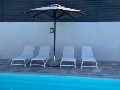 three chairs and an umbrella next to a swimming pool at LA POINTE D’ASPRETTO in Ajaccio