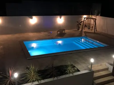a large swimming pool in a backyard at night at LA POINTE D’ASPRETTO in Ajaccio