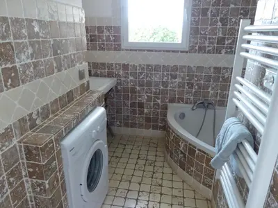 a bathroom with a tub and a washing machine at BAVELA in Porto-Vecchio