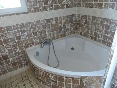 a bath tub in a tiled bathroom with a shower at BAVELA in Porto-Vecchio