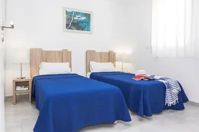 two beds with blue sheets in a room at Résidence Odalys Acqua Bella in Poggio-Mezzana