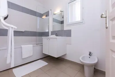 a white bathroom with a sink and a toilet at Résidence Odalys Acqua Bella in Poggio-Mezzana