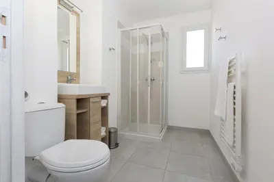 a white bathroom with a toilet and a shower at Résidence Odalys Acqua Bella in Poggio-Mezzana