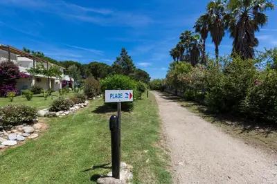 a sign in the grass next to a dirt road at Résidence Odalys Acqua Bella in Poggio-Mezzana