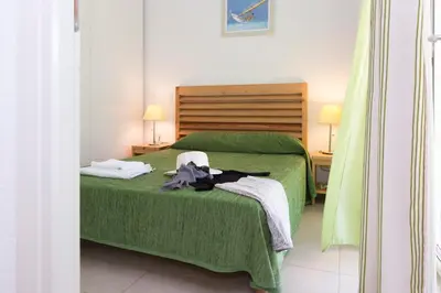 a bedroom with a green bed and two lamps at Résidence Odalys Acqua Bella in Poggio-Mezzana