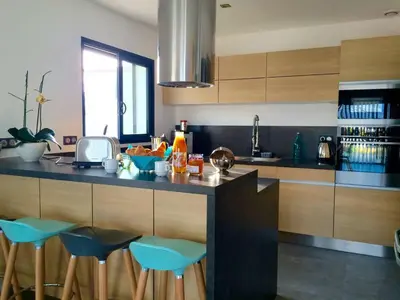 a kitchen with a counter with blue bar stools at Villa entre Mer et Montagne... in Calenzana