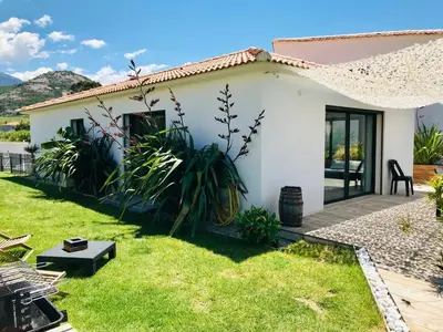 a small white house with a grass yard at Villa entre Mer et Montagne... in Calenzana