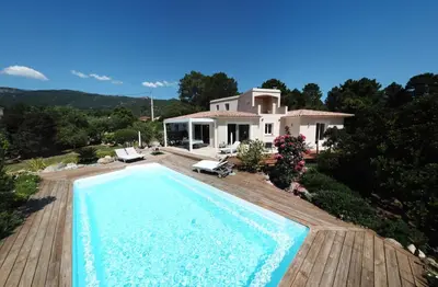 a villa with a swimming pool in front of a house at A BARMETTA in Porto-Vecchio