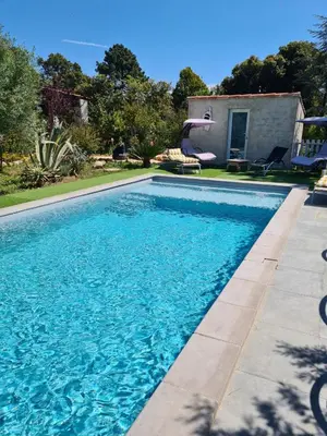a swimming pool with blue water in front of a house at Casa San Niolo in Cervione