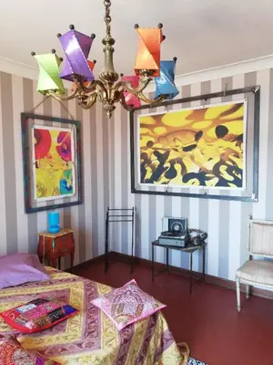 a bedroom with a bed and a painting and a chandelier at Villa Cécile in Ajaccio