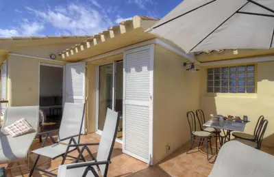 a patio with a table and chairs and an umbrella at Appartement 2 pièces Pied dans l'eau in Porto-Vecchio