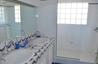 a white bathroom with two sinks and a shower at Appartement 2 pièces Pied dans l'eau in Porto-Vecchio