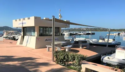 a marina with benches and boats in the water at Appartement 2 pièces Pied dans l'eau in Porto-Vecchio