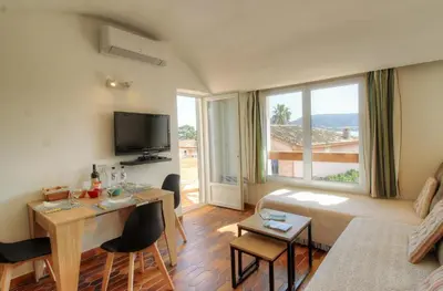 a living room with a couch and a table with chairs at Appartement 2 pièces Pied dans l'eau in Porto-Vecchio