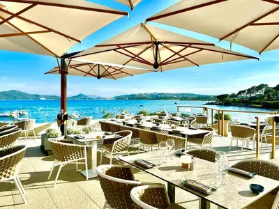 a restaurant with tables and chairs and umbrellas at Appartement 2 pièces Pied dans l'eau in Porto-Vecchio