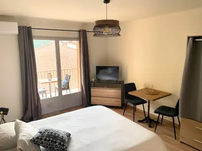 a bedroom with a bed and a table and a television at Les résidences du port appartements meublés in Porto Ota