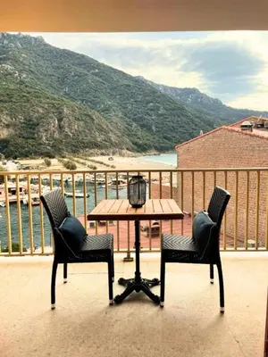 a table and chairs on a balcony with a view of a beach at Les résidences du port appartements meublés in Porto Ota