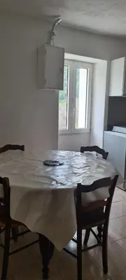 a dining room table with chairs and a white table cloth at maison de village T4 in Poggio-dʼOletta