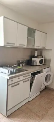 a kitchen with white cabinets and a washing machine at maison de village T4 in Poggio-dʼOletta
